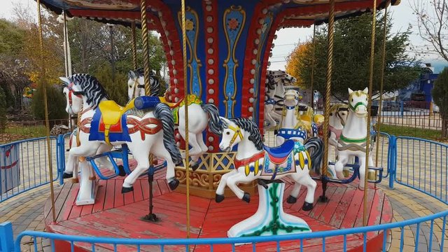 Old fashioned carousel horses in autumn park. Steadicam shot.
