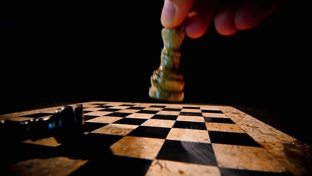 4K footage of a chess board on a black background with a black king on it, a white king hits the black and stands on his place...