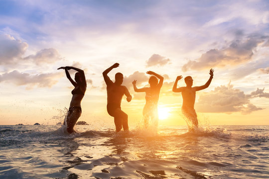 Young people having fun splashing water in the sea, friends