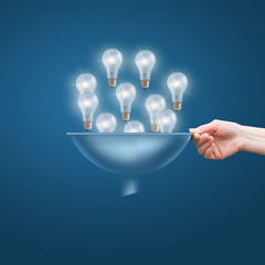 Hand with a funnel and a lot of bulbs, the concept of lots of business ideas