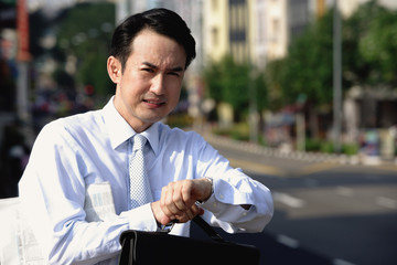Businessman looking at watch, frowning