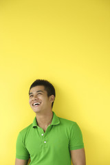 Obraz premium Man standing against yellow wall, smiling, looking up