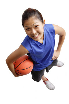 Young woman holding basketball, smiling at camera