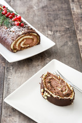 Chocolate yule log cake with red currant on wooden background
