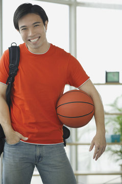 Man in red T shirt and jeans, holding basketball
