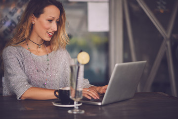 Young woman typing on the laptop in the cafe