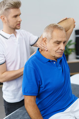 physiotherapeut untersucht die schulter eines älteren mannes in der praxis
