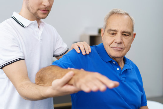 orthopäde untersucht die schulter eines älteren patienten
