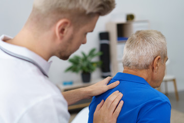 physiotherapeut untersucht den rücken eines älteren mannes