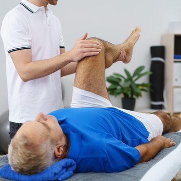 therapeut untersucht das knie eines älteren mannes