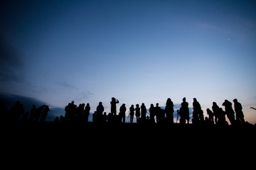 Silhouette of a group of people waiting for sun rise at the mountain peak with dramatic sky,...