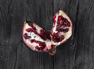 sliced pomegranate on a black wooden table close-up, top view