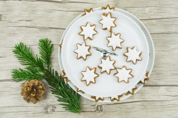 Etagere, Teller mit Weihnachtsgebäck, Zimtsterne, links ein Tannenzweig mit einem Tannenzapfen und...