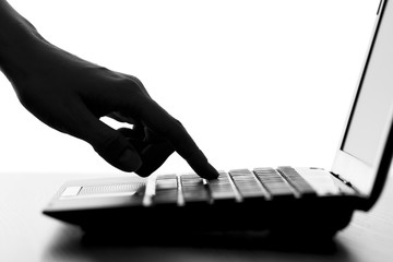 silhouette of the finger of a female hand press a key on the keyboard of the netbook