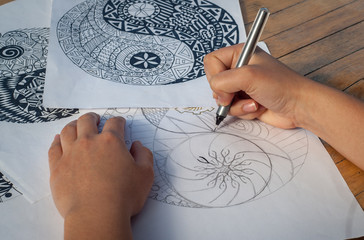 Hand of woman drawing yin yang for adult anti stress coloring book