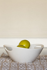 green apples in white bowl on kitchen table