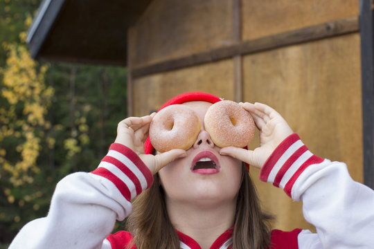 A Teenage Girl Being Silly Holding Two Donuts Over Her Eyes In Sagle, Idaho.