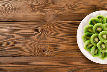 Fresh slices of kiwi on a wooden background, top view