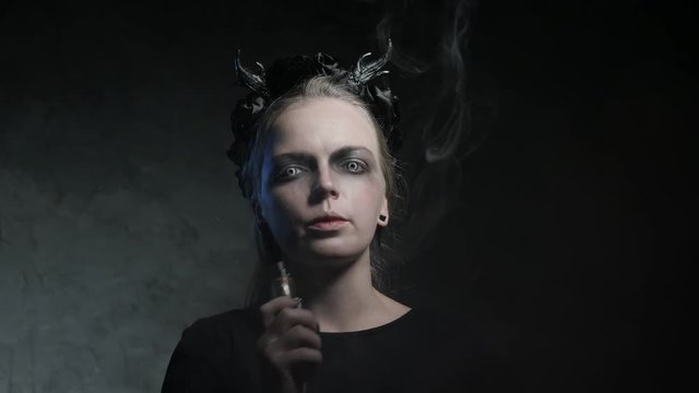 Dark portrait of evil witch with vaporizer. 4K UHD