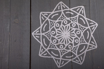 White mandala on dark wooden background