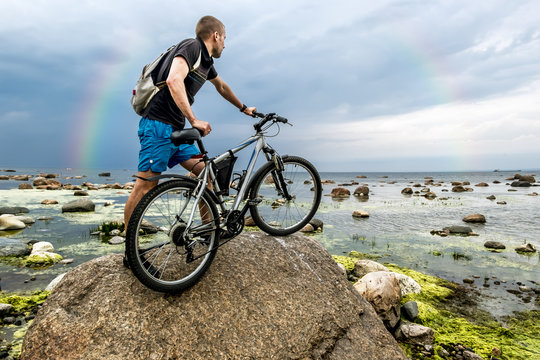The cyclist with his bike looking at the horizon of the sea and