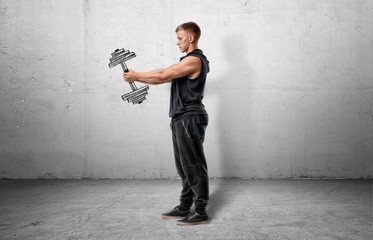 Muscular sportsman full-height standing and holding a dumbbell, drawn on grey wall.