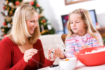 Christmas: Girl Helping Mother With Fun Popcorn Garland Decorati