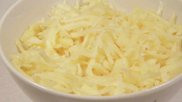 Grated cheese in a bowl. Rotation.