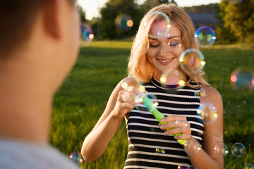 A beautiful girl with a happy smile blowing soap bubbles on the