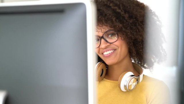 Cheerful mixed-race girl designing in office on computer