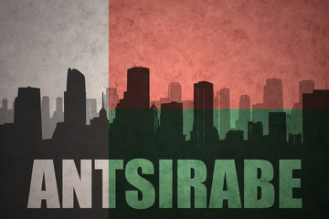 abstract silhouette of the city with text Antsirabe at the vintage madagascar flag