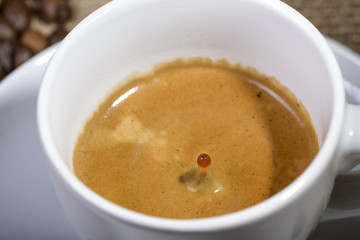 macro drop of coffee in fall toward the cup of coffee