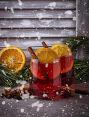 Fototapeta na wymiar Glasses of mulled wine with orange and cinnamon, snow effect