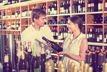 Portrait of male and female customers picking bottle of wine