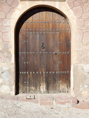 Fototapeta na wymiar Puerta de madera con remaches y arco de medio punto