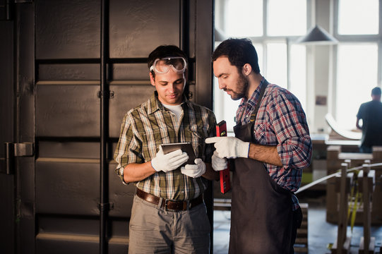 profession, technology and people concept - two workmen with tablet pc computer at workshop