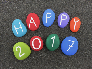 Happy 2017 on colored stones over volcanic black sand 