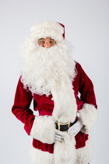 Santa Claus in eyeglasses and red costume staying on white background and looking into camera. American shot