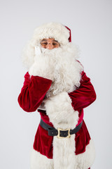 Santa Claus in eyeglasses and red costume staying on white background and looking into camera. American shot
