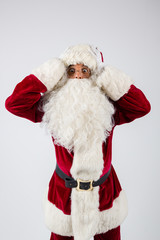 Santa Claus in eyeglasses and red costume put hands on head against white background and looking into camera. American shot