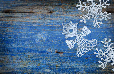 Knitted snowflakes and angel on blue wooden background