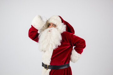 Santa Claus in eyeglasses and red costume make a point with hands on white background and looking into camera. Medium shot
