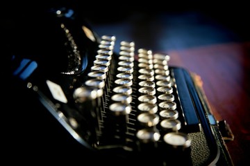 Old black typewriter on dark background with shiny keys