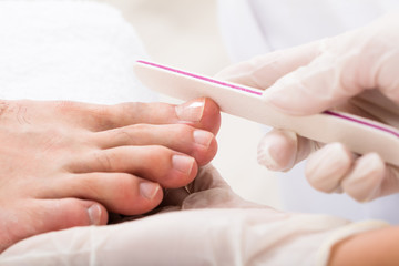 Beautician Hand Filling Person's Nail