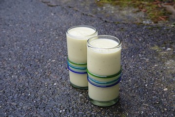 Two healthy drinks, yellow mango smoothies on wet concrete