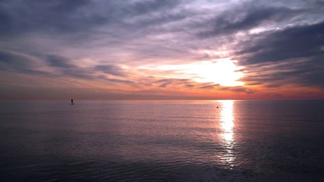 Ocean sunset. Man on surfboard at sunset ocean. Sunset at ocean with calm water. Sunset ocean. Ocean landscape at sunset. Sunset clouds over ocean. Sunset sky over calm water. Sunset water