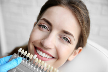 Young woman choosing color of teeth at dentist