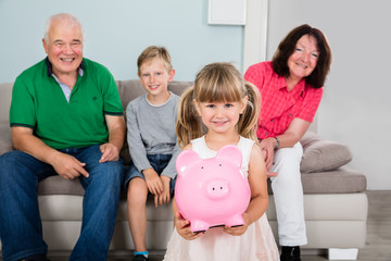 Granddaughter Holding Piggybank At Home