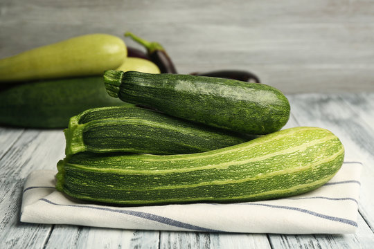 Composition with fresh zucchini and napkin on blurred gray background