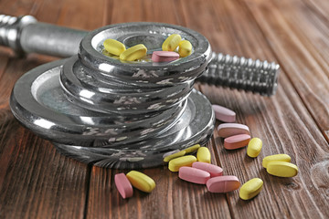 Weight disks and drugs on wooden background